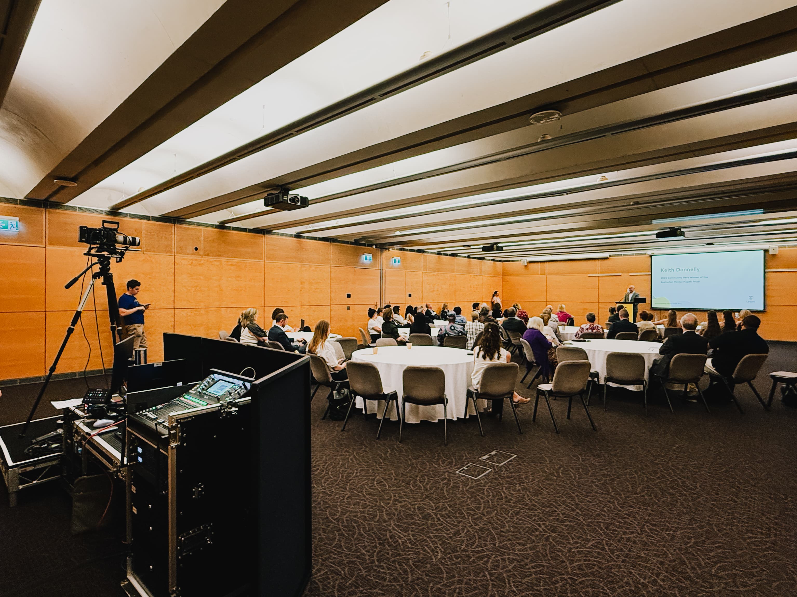 Corporate leadership forum setup with audience seating, projector screen, and AV control position.
